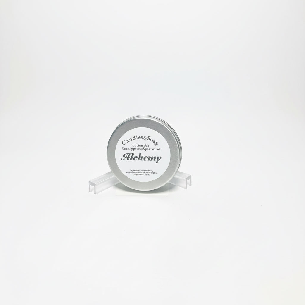 A solid lotion bar presented in a metal tin with a label that reads 'Alchemi'. The tin is placed on a white surface with a wooden background.