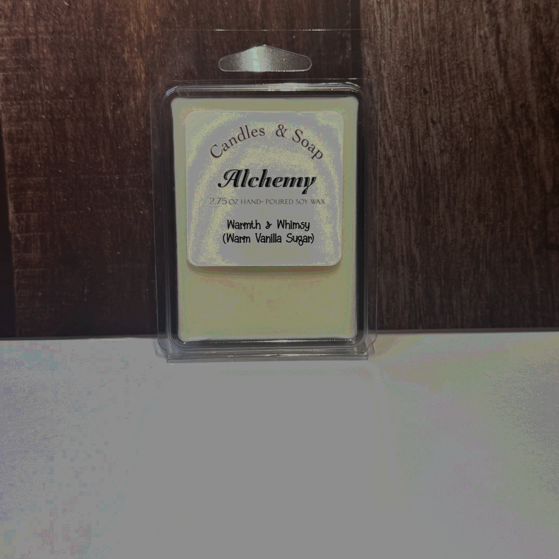 Candle wax melt package labeled 'Alchemy' on a wooden surface