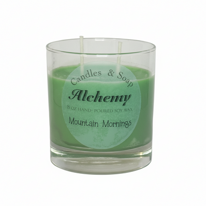 Candle in a glass jar with 'Alchemy' label on a white background