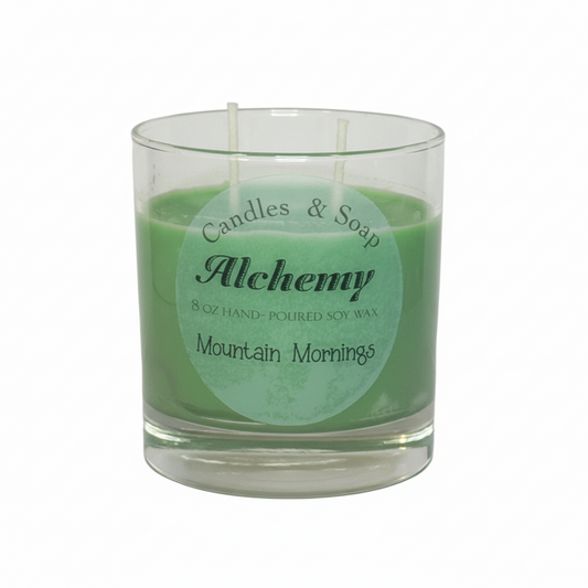 Candle in a glass jar with 'Alchemy' label on a white background