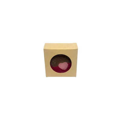 Small round pink bath bomb in a cardboard box on a white background