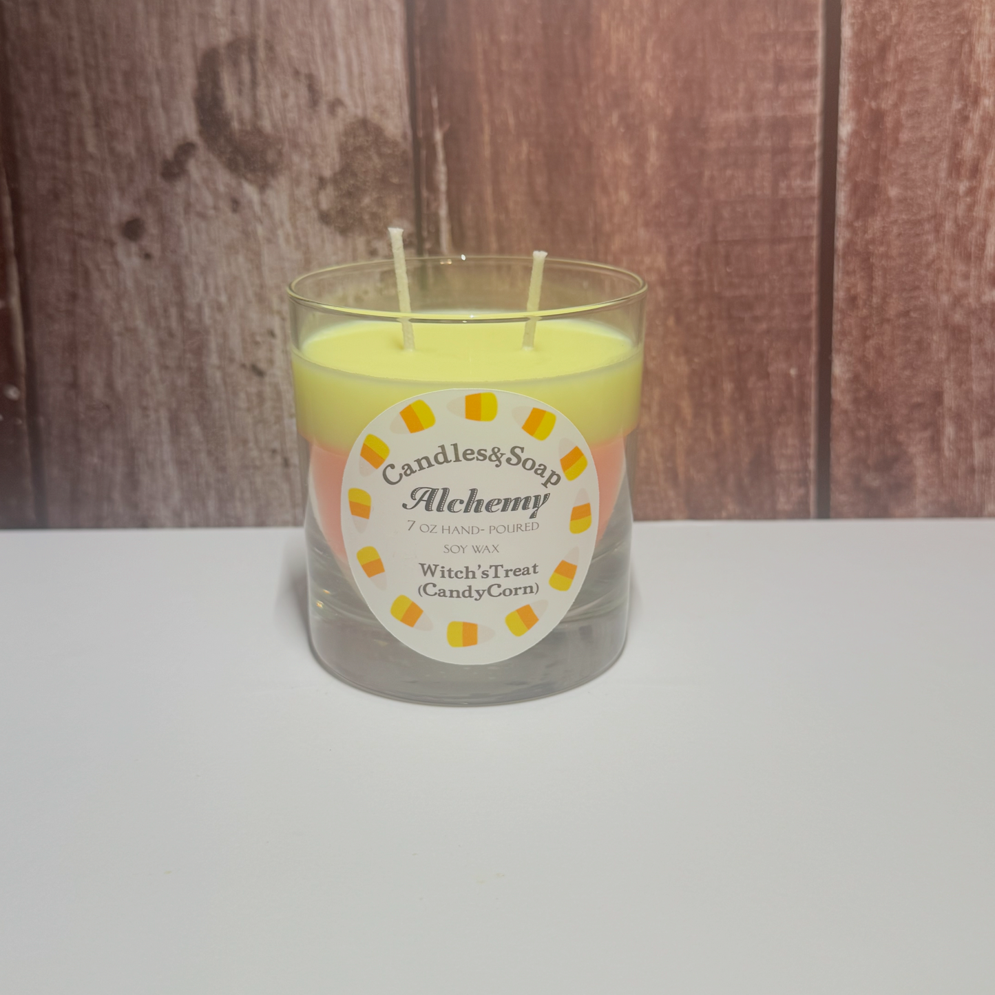 Candle in a glass jar with a label on a wooden surface